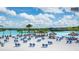 A beach scene with blue lounge chairs and umbrellas on a white sand beach with blue sky at 7811 Roma Dune Dr, Wesley Chapel, FL 33545