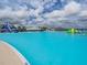 View of a bright blue lagoon with an inflatable slide and lounge chairs on the beach at 7811 Roma Dune Dr, Wesley Chapel, FL 33545