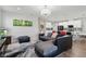 Open living area featuring wood floors, modern lighting, a comfortable sofa, and a seamless connection to the kitchen at 7811 Roma Dune Dr, Wesley Chapel, FL 33545