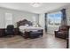 A well-lit main bedroom features wood floors, a large window with curtains, and comfortable seating area at 7811 Roma Dune Dr, Wesley Chapel, FL 33545
