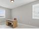 Bright home office with a wooden desk and chair and light from two windows at 7811 Roma Dune Dr, Wesley Chapel, FL 33545