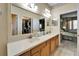 Bathroom featuring double sinks with cabinets, a large mirror, and doorways to the bedroom and walk-in closet at 8141 Ambersweet Pl, Land O Lakes, FL 34637