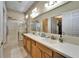 Bright bathroom featuring a large mirror, double sinks, a glass-enclosed shower, and classic fixtures at 8141 Ambersweet Pl, Land O Lakes, FL 34637