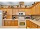 Kitchen with white appliances, light wood cabinets and patterned wallpaper at 8141 Ambersweet Pl, Land O Lakes, FL 34637