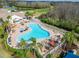 Aerial view of a kidney-shaped pool with lounge chairs and umbrellas, beside a clubhouse and golf course on a sunny day at 8141 Ambersweet Pl, Land O Lakes, FL 34637