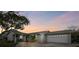 Charming home with a well-manicured yard, mature tree and attached two car garage at sunset at 8448 Flagstone Dr, Tampa, FL 33615