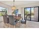 A well-lit dining room with a table and chairs that are under a modern light fixture with sliding glass door access to the porch at 9222 134Th St, Seminole, FL 33776