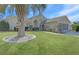 Beautifully landscaped one-story home featuring a paver driveway, lush lawn, and mature palm trees at 10302 Belltower St, Spring Hill, FL 34608