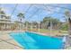 Screened-in pool with brick paver deck, lush tropical landscaping, and clear blue skies at 10302 Belltower St, Spring Hill, FL 34608