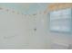 Well-lit shower space with white tile, accent trim, grab bar, and window at 10302 Belltower St, Spring Hill, FL 34608