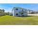 Wide backyard with a blue home, green grass, and a covered patio at 10642 Mistflower Ln, Tampa, FL 33647