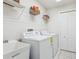 Well-equipped laundry room with washer, dryer, shelving, and utility sink at 10642 Mistflower Ln, Tampa, FL 33647