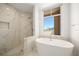 Bright bathroom features a soaking tub and walk-in shower with marble-look tile surround and large window at 11 San Marco St # 307, Clearwater Beach, FL 33767