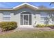 Inviting front entrance with an arched door, well-maintained landscaping, and a charming, light green exterior at 1205 Huntington Greens Dr, Sun City Center, FL 33573