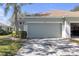 A home's two-car garage, with light green paint and well manicured front yard landscaping at 1205 Huntington Greens Dr, Sun City Center, FL 33573