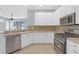 Eat-in kitchen with white cabinets, stainless steel dishwasher, and granite countertops at 1205 Huntington Greens Dr, Sun City Center, FL 33573