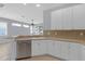 Bright kitchen features a stainless steel dishwasher, white cabinets, and flows into the open living space at 1205 Huntington Greens Dr, Sun City Center, FL 33573