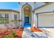 Charming home featuring a blue front door, manicured landscaping, and a covered entryway at 12821 Lake Vista Dr, Gibsonton, FL 33534