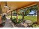 Inviting covered porch with outdoor seating, potted plants, and scenic views of the lush backyard and serene lake at 17119 Rainbow Ter, Odessa, FL 33556