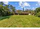 Expansive green backyard with a well-maintained lawn, mature trees, and a charming single-story home at 17119 Rainbow Ter, Odessa, FL 33556