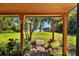 Picturesque view of the backyard through a rustic pergola, showcasing a manicured lawn and tranquil lake at 17119 Rainbow Ter, Odessa, FL 33556
