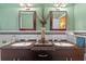 Bathroom with a dual sink vanity, granite counters, decorations, and two mirrors at 17119 Rainbow Ter, Odessa, FL 33556
