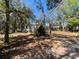 This exterior view showcases a simple home surrounded by mature trees and natural landscaping at 17233 Dalberg Dr, Spring Hill, FL 34610