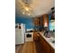 Galley kitchen has wood cabinets, white appliances, bright lighting, and light hardwood floors at 17233 Dalberg Dr, Spring Hill, FL 34610