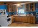 Farmhouse kitchen featuring wood cabinets, blue walls, hardwood floors and a white refrigerator at 17233 Dalberg Dr, Spring Hill, FL 34610