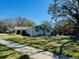 Single-story home with a lush green lawn and mature trees, offering a serene and inviting curb appeal at 2343 Wilshire Dr, Dunedin, FL 34698