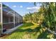 A well-maintained backyard with a screened-in patio and tropical landscaping at 2769 Harvest Drive, Sarasota, FL 34240