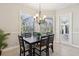 Bright dining room with modern chandelier, large windows with backyard view, and neutral walls at 2769 Harvest Drive, Sarasota, FL 34240