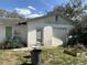 Exterior side view of a garage with a large garage door and patchy landscaping around the property at 38714 C Ave, Zephyrhills, FL 33542