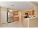 Open kitchen features stainless steel refrigerator, light wood cabinets, breakfast bar, and tile floors at 4216 Preserve Pl, Palm Harbor, FL 34685