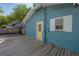 A cozy blue home with a yellow door and a spacious wooden deck at 5603 N Taliaferro Ave, Tampa, FL 33604