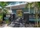 Inviting front porch featuring a bright yellow front door with glass panels and sleek, dark painted steps at 5603 N Taliaferro Ave, Tampa, FL 33604