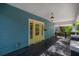 Spacious front porch with a vibrant yellow door and side windows, offering a bright and welcoming entrance at 5603 N Taliaferro Ave, Tampa, FL 33604