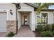 Charming front entryway with a stone pillar, lush landscaping, and a covered doorway at 5614 Silverside Pine Ct, Lakewood Ranch, FL 34211