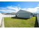 Exterior view of the house showcasing the backyard with a lush green lawn and white fence at 6863 Hanworth Ln, Zephyrhills, FL 33541