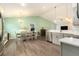 Open floorplan with dining area next to the modern kitchen and light green accent wall at 6863 Hanworth Ln, Zephyrhills, FL 33541
