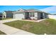Single-story home with a gray exterior, two car garage, tidy landscaping and a concrete driveway and walkway at 6863 Hanworth Ln, Zephyrhills, FL 33541