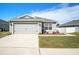 Charming single-story home with gray exterior, well-manicured lawn, and an attached two-car garage at 6863 Hanworth Ln, Zephyrhills, FL 33541