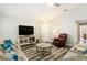 Well-lit living room features a large TV, a cozy reading chair, and stylish decor throughout the open space at 6863 Hanworth Ln, Zephyrhills, FL 33541