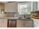 Bright kitchen features a stainless steel sink, dishwasher, white cabinetry, and a window with natural light at 510 Pine S Ave, Oldsmar, FL 34677