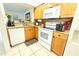 Galley kitchen featuring granite counters, wood cabinets, white appliances, and a tile floor at 10131 Lake Oak Cir, Tampa, FL 33624