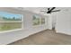 Bright bedroom featuring ample natural light, ceiling fan and modern gray wood-look flooring at 1054 W Baffin Dr, Venice, FL 34293