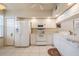 Well-lit kitchen with white appliances, cabinetry, tile flooring, and a decorative rug at 1400 Water View W Dr # 102, Largo, FL 33771