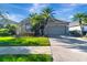 Charming single-story home with a well-manicured lawn, palm trees, and a two-car garage at 1453 Appleton Pl, Wesley Chapel, FL 33543