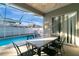 Covered outdoor patio with a marble top table, six chairs, a screened-in pool and beautiful blue skies above at 1453 Appleton Pl, Wesley Chapel, FL 33543