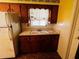 Kitchen with wooden cabinets, a window over the sink, and dated white appliances at 1620 Dander Dr, Holiday, FL 34690